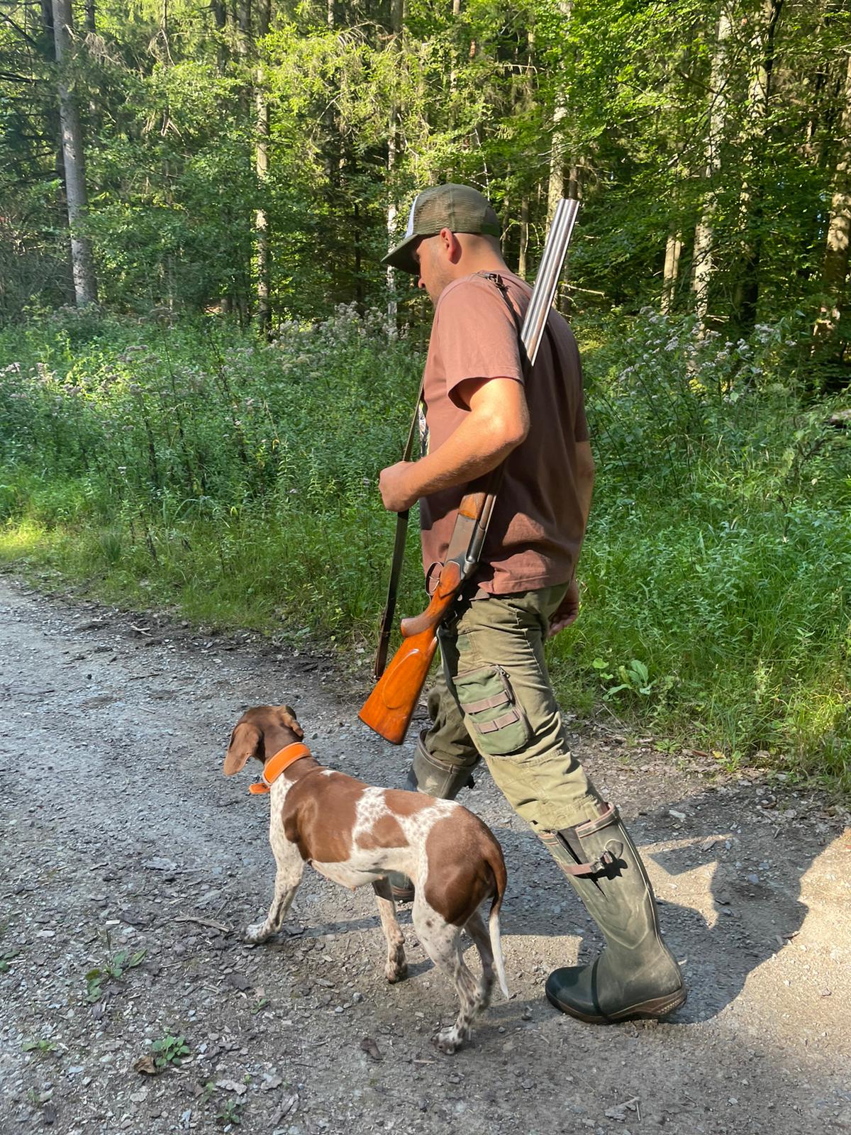 Jäger mit Hund auf Waldweg